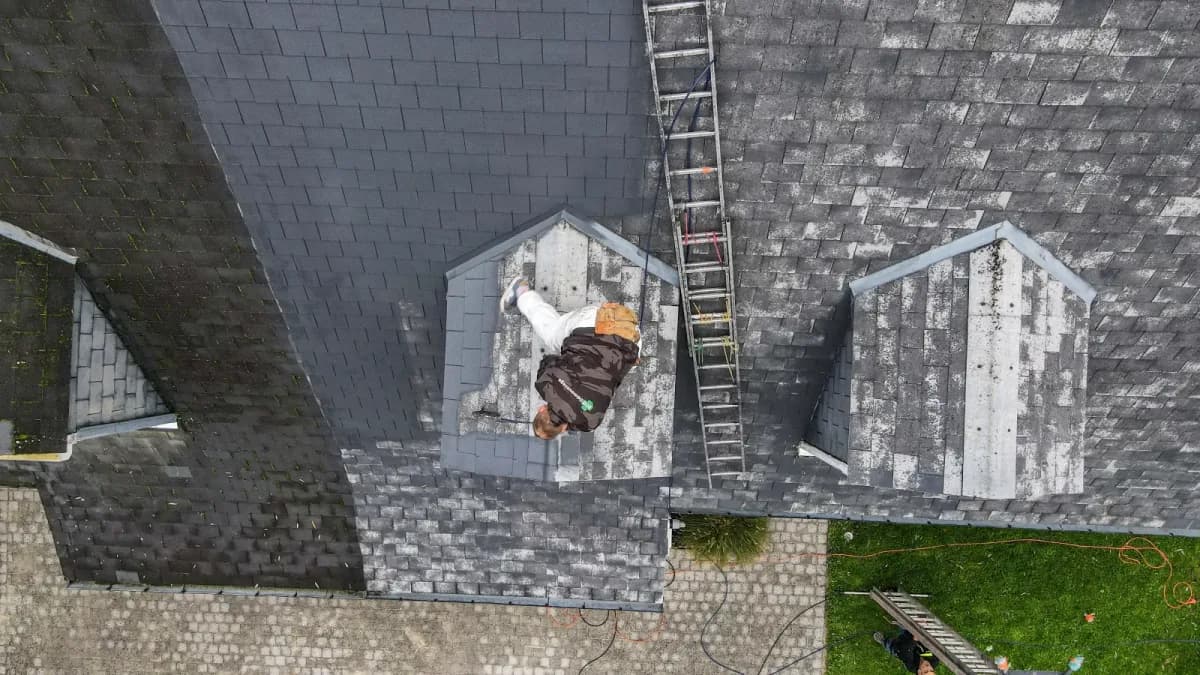 Roofer at the dormer of a slate roof, top-down view