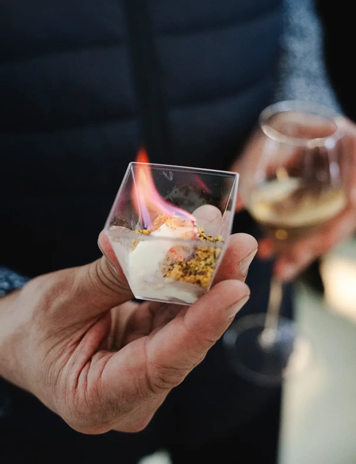 Flambéed dessert in a glass, held in a hand