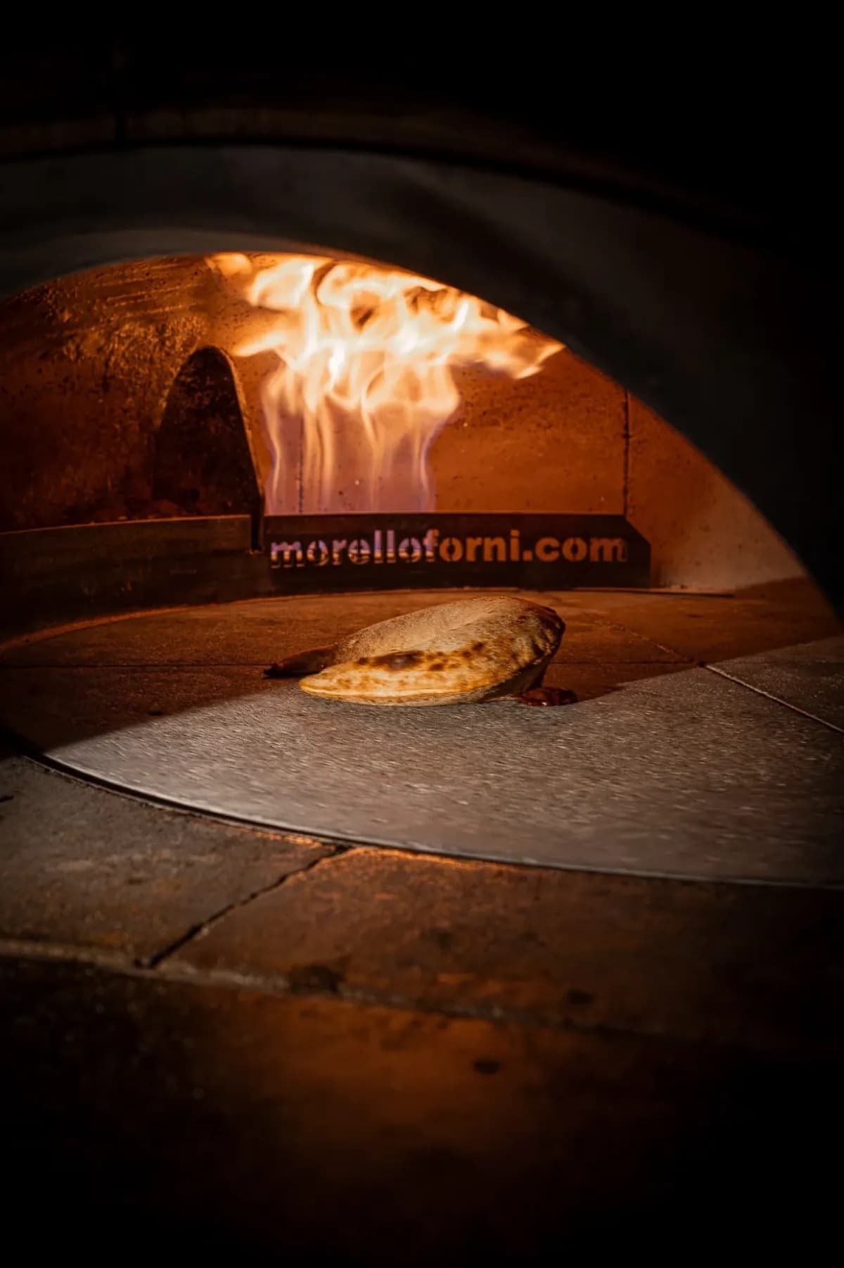 Horno de leña encendido, con una pizza cociéndose