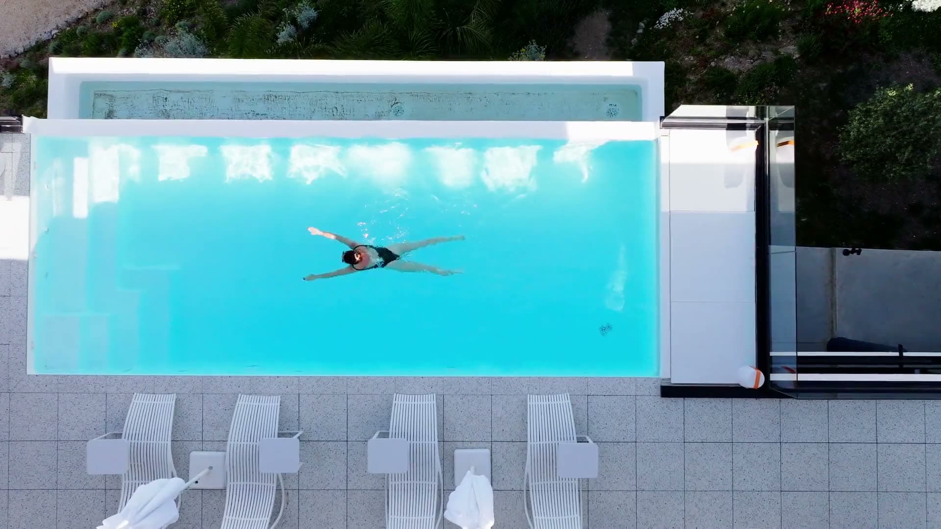 Top-down shot over a pool, a swimmer in frame
