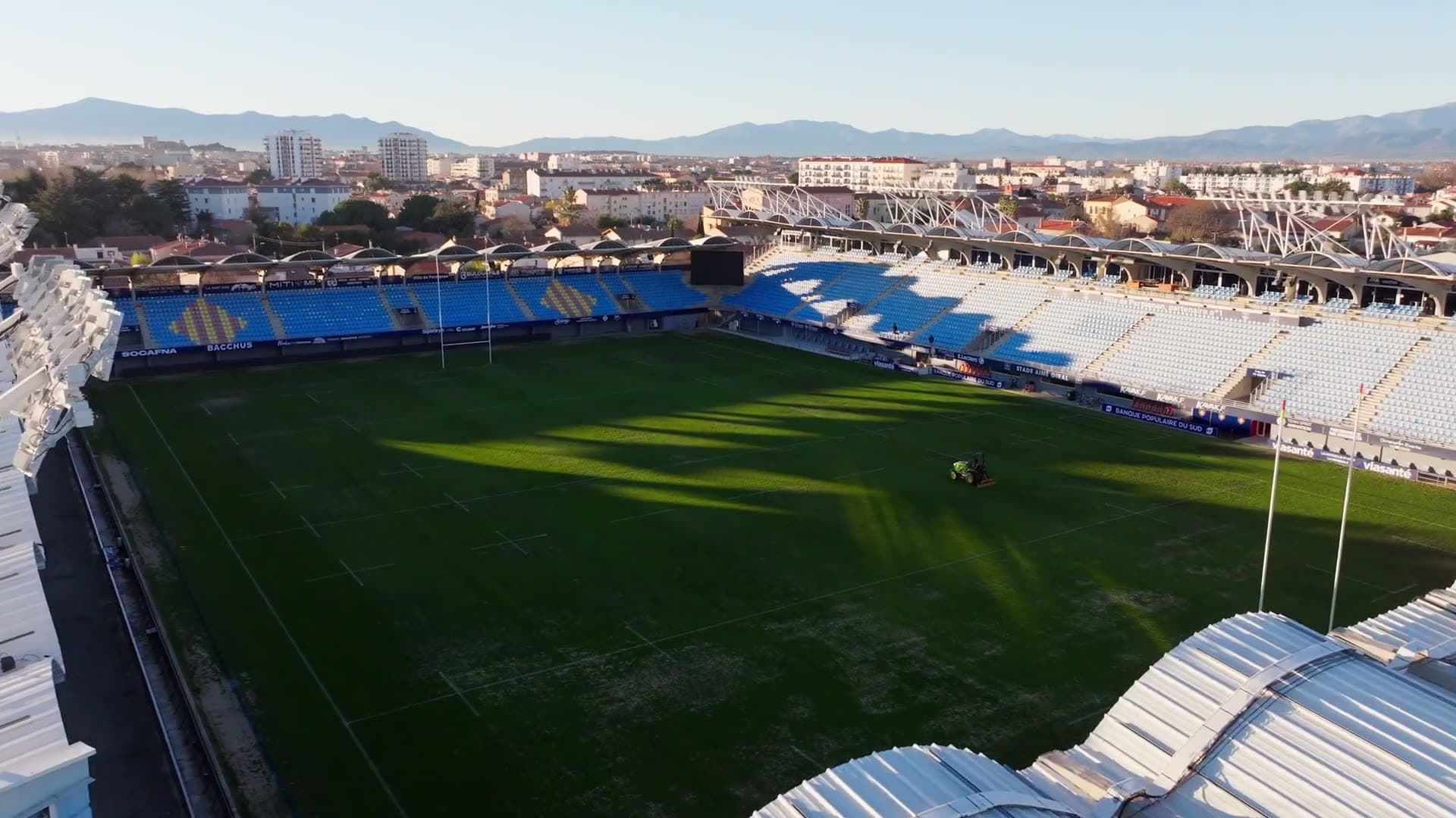 Flight over a rugby stadium in low, raking light