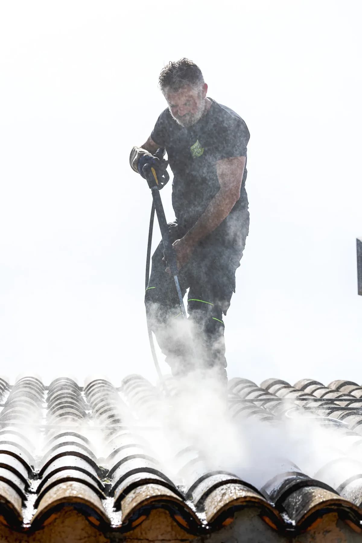 Worker cleaning a roof with a pressure washer