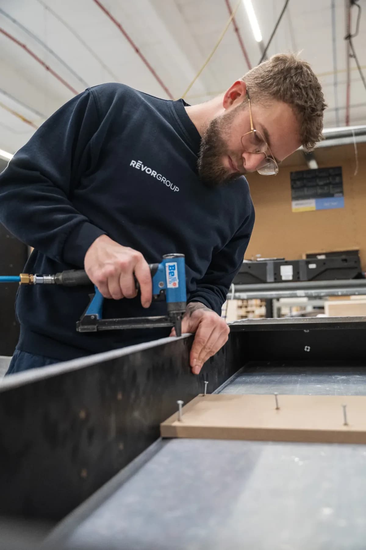 Craftsman screwing together a black cabinet in his workshop