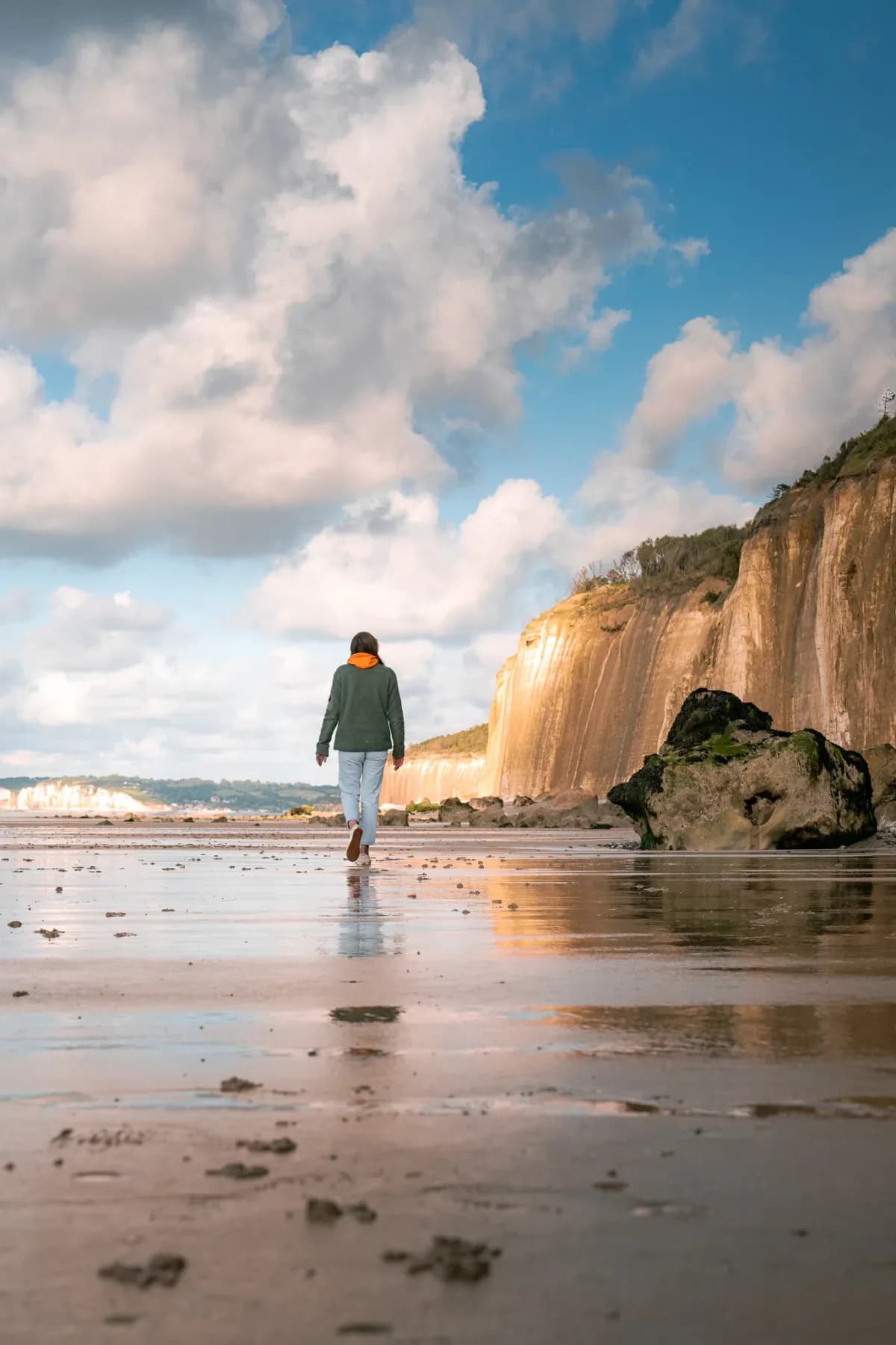 Walker on a beach at the foot of the cliffs