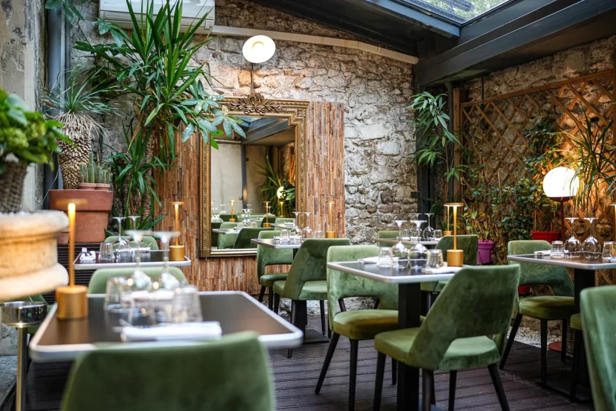 Dining room with stone walls, plants and green armchairs
