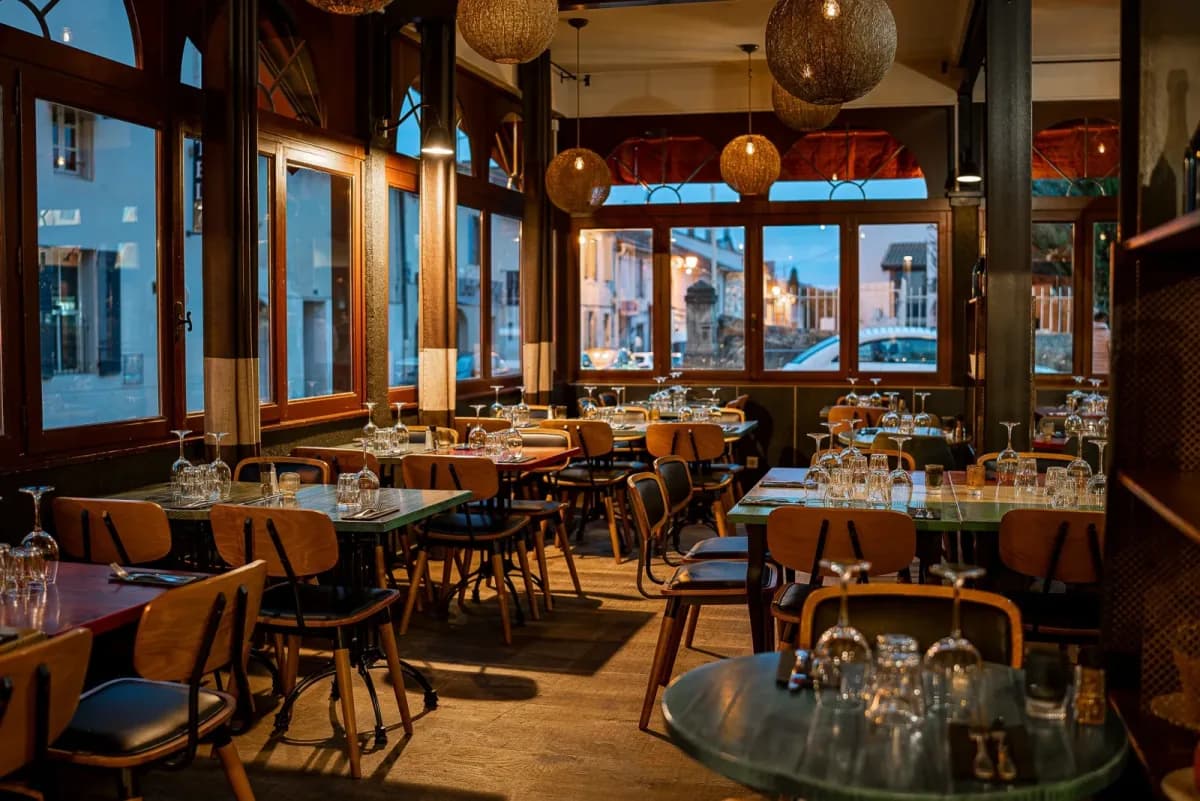 Restaurant dining room with tables laid, opening onto large windows
