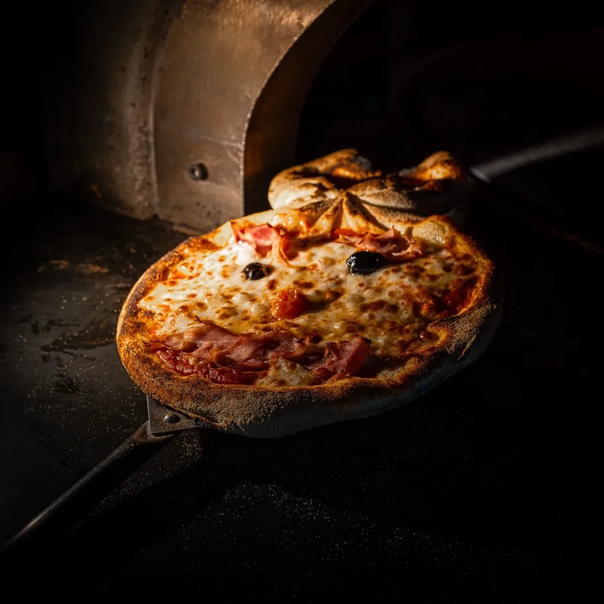 Pizza fresh from the wood-fired oven, on the peel