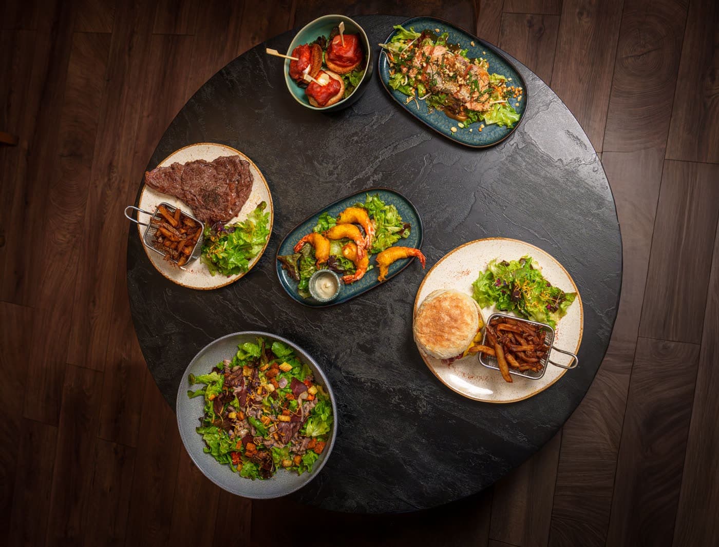 Table ronde vue du dessus : salades, burger, frites et crevettes, Le Jardin de Lana