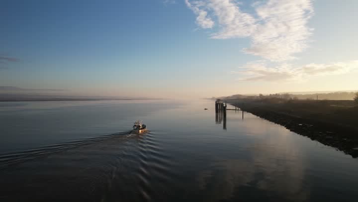 Boat on a canal in low sunlight, seen from a drone